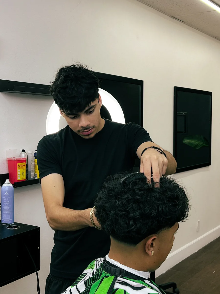 Barber shaping a curly-top haircut